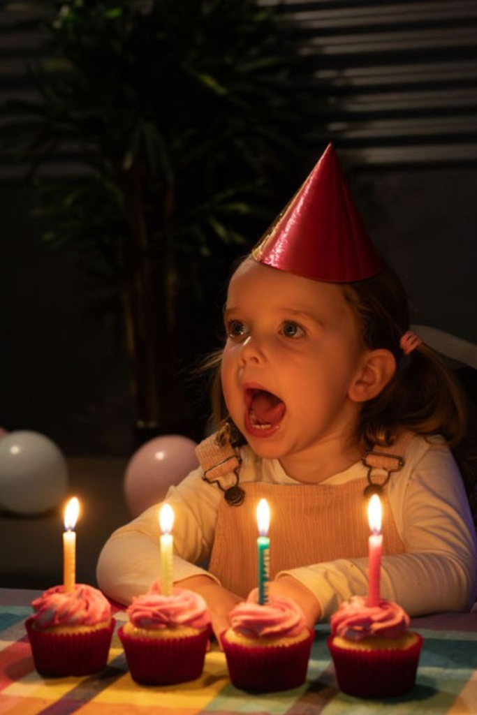 Young girl celebrating with birthday cupcakes and candles