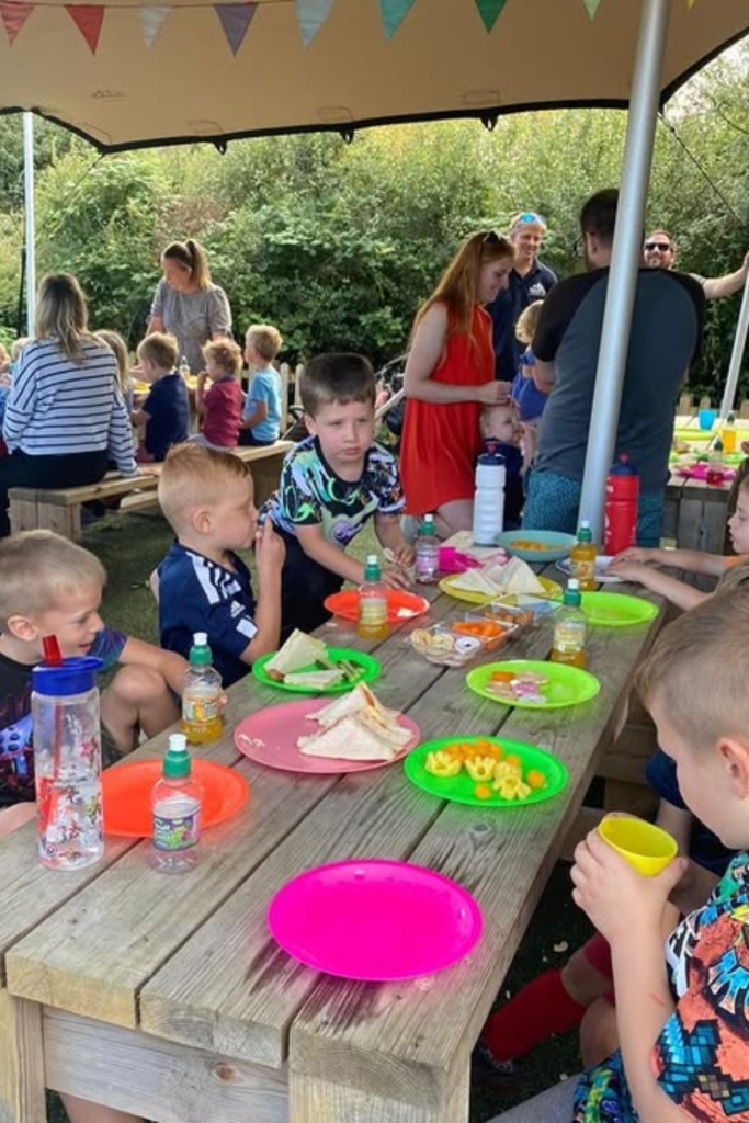 Children eating together at an outdoor birthday picnic table