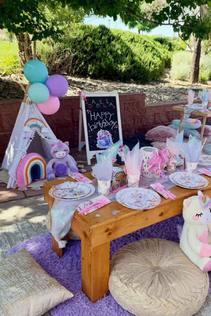 Unicorn outdoor birthday table with pastel balloons and teepee