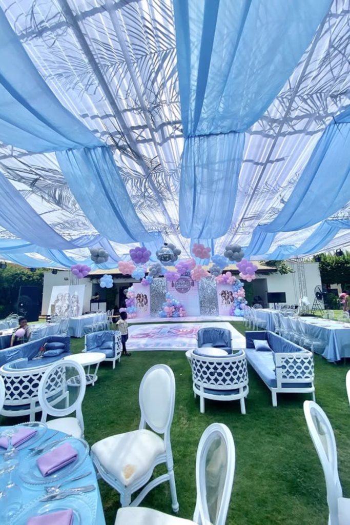 Blue canopy outdoor birthday lounge with sofas and balloons