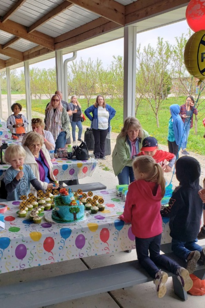 Covered outdoor birthday cake table with cupcakes and balloons