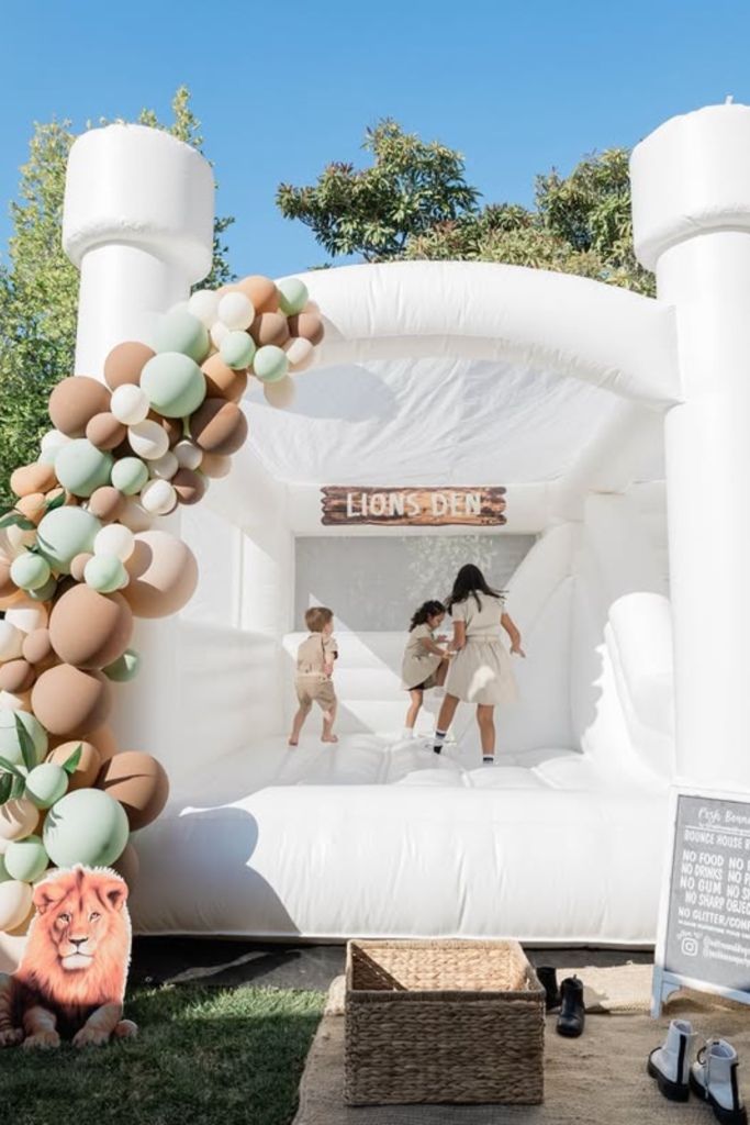 White outdoor bounce house with safari balloon decorations