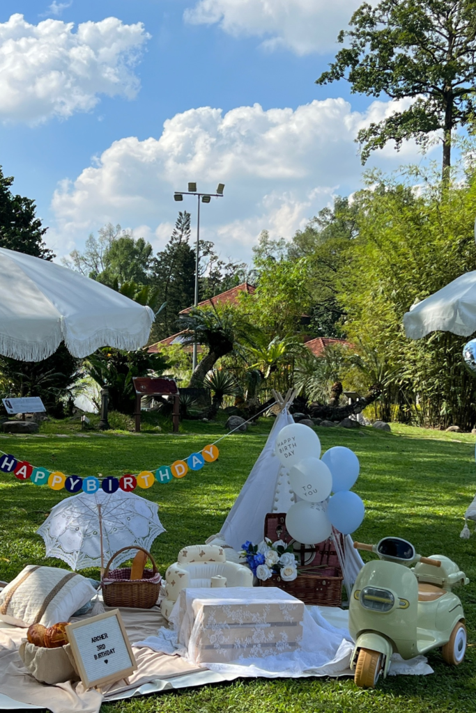 Outdoor teepee birthday picnic corner with pillows and umbrellas