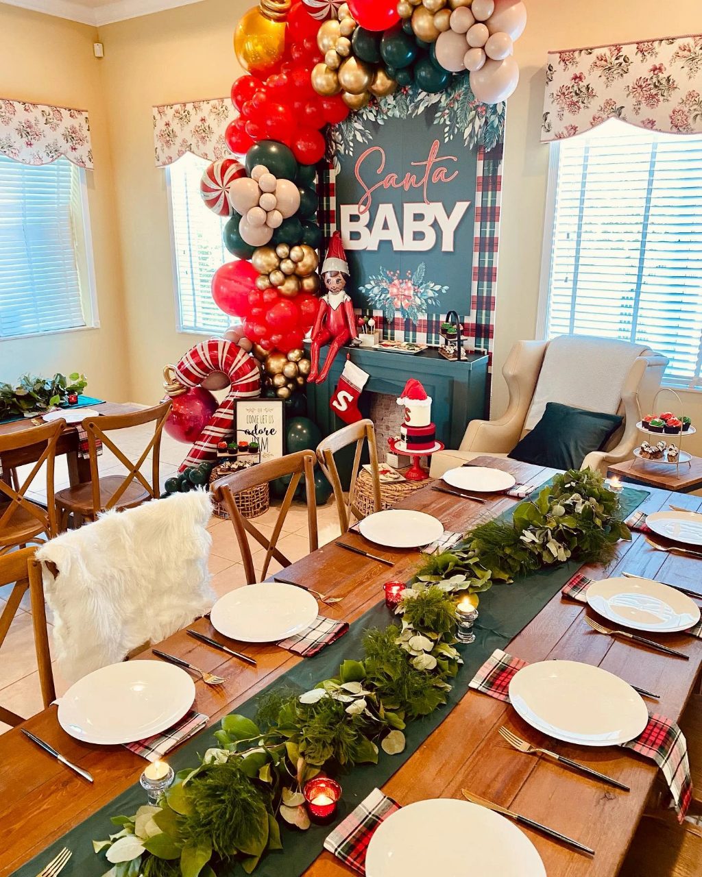 Santa Baby garland backdrop display with red and green balloons, candy canes, greenery, and holiday table decor