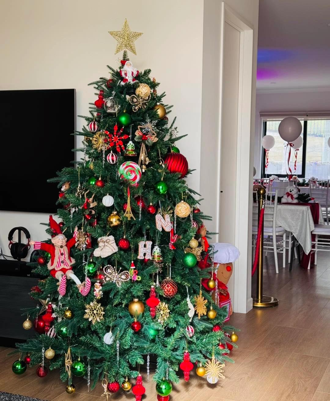 Decorated Christmas tree display with colorful ornaments, elf figurines, and festive baby shower tables