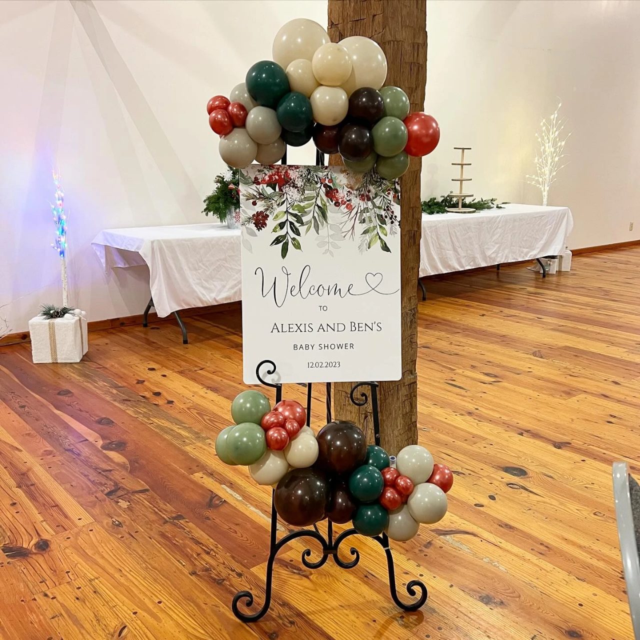 Floral Santa Baby entry sign with earthy balloons and red seasonal accents