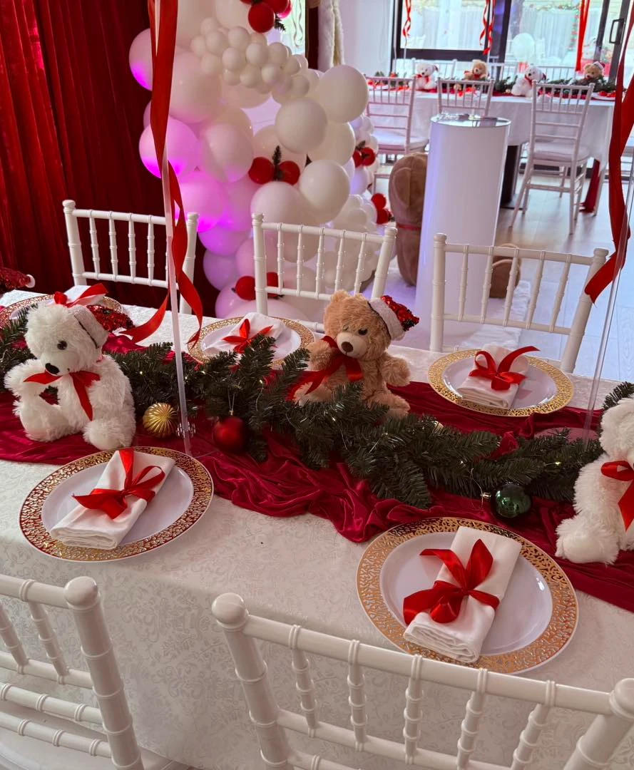 Santa Baby table setting with teddy bears, evergreen garlands, gold plates, and red napkins