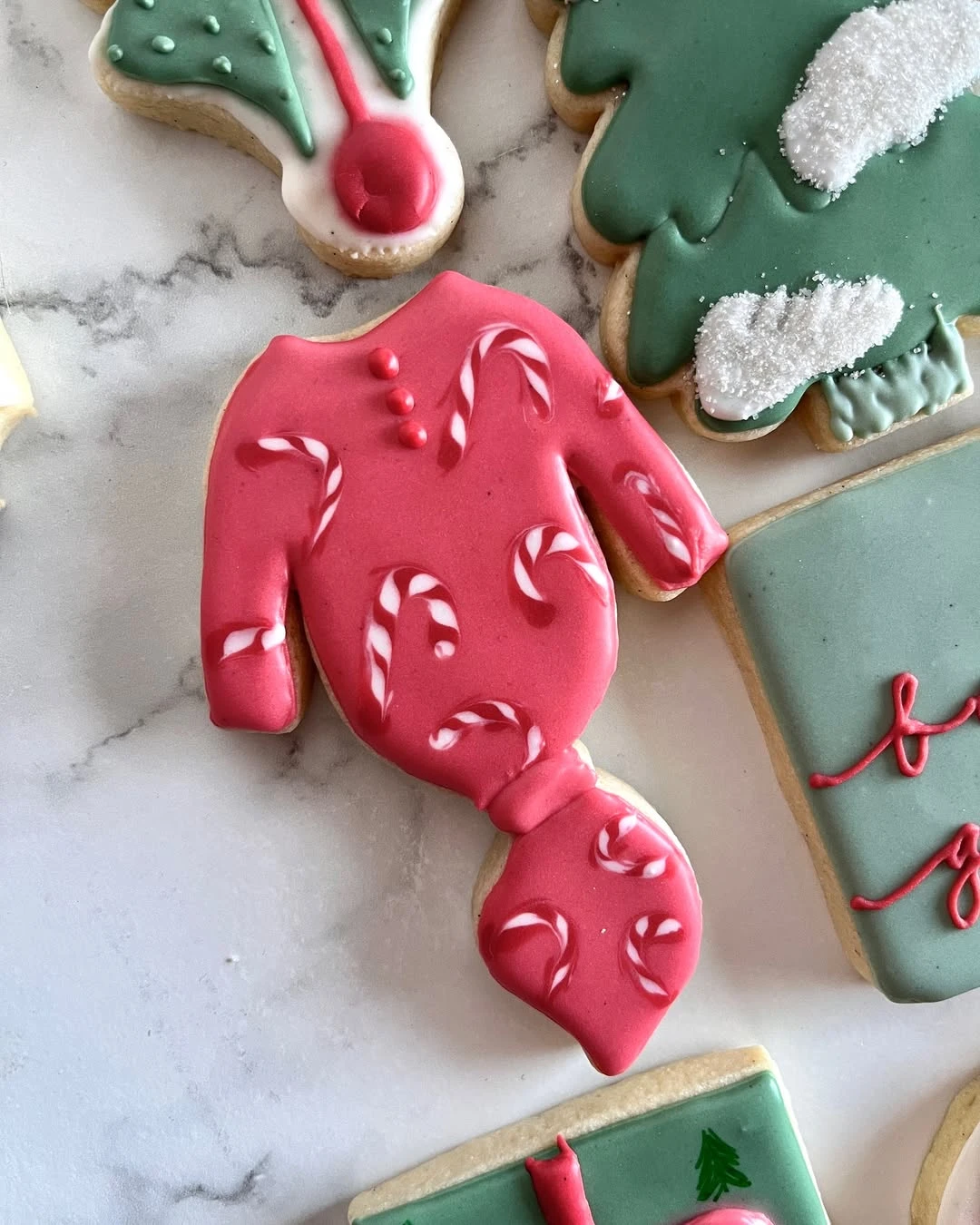 Pink baby onesie sugar cookie decorated with white candy cane swirls